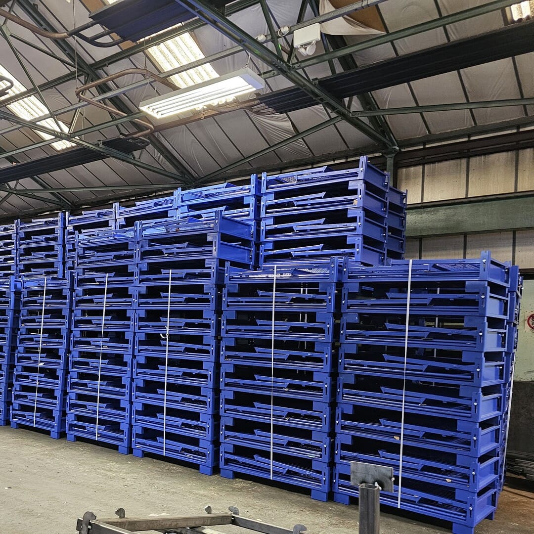 Warehouse full of stacked blue glitterboxes & collapsible pallet cages.