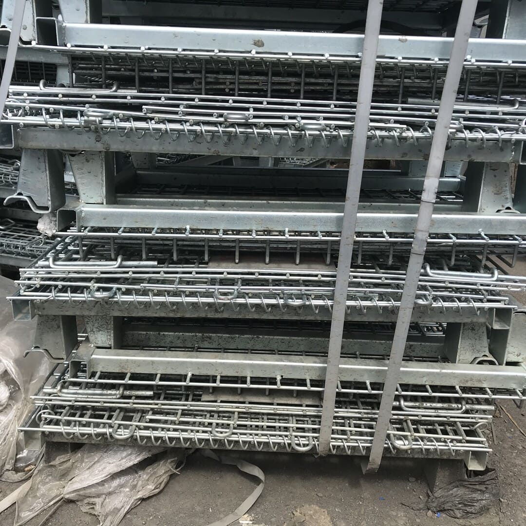 Used unpainted collapsible metal pallet cages stacked up.