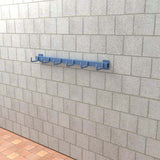 Real life mock up of blue heavy duty wall mounted hooks mounted onto a brick wall.